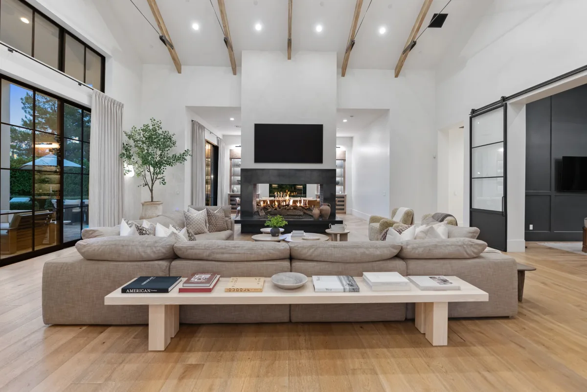 Complete great room with timber ceiling beams, pale seating and a central fireplace