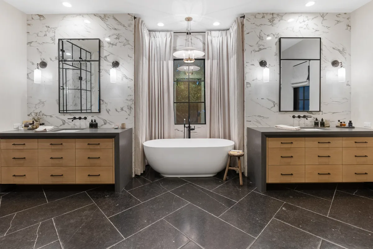 Freestanding bath centered between two marble bathroom vanities