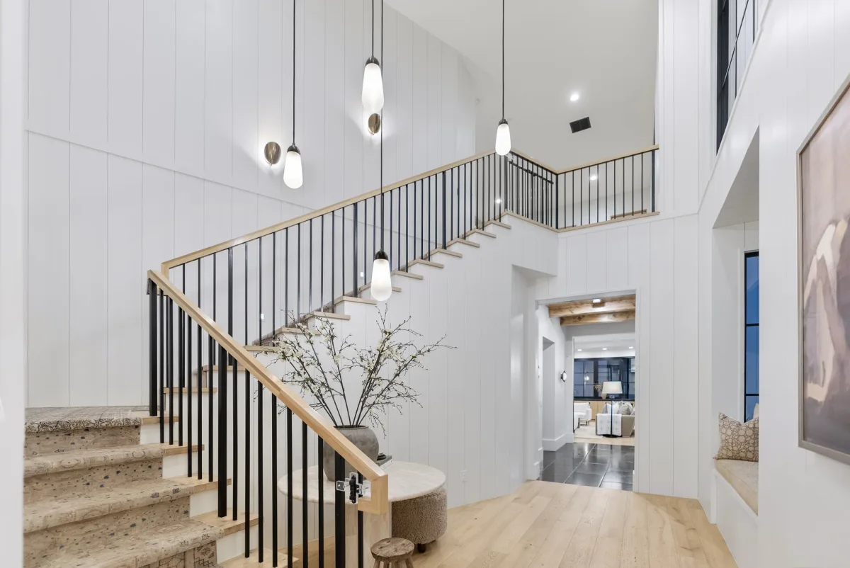 Open staircase with pale wood handrails and slender dark balusters