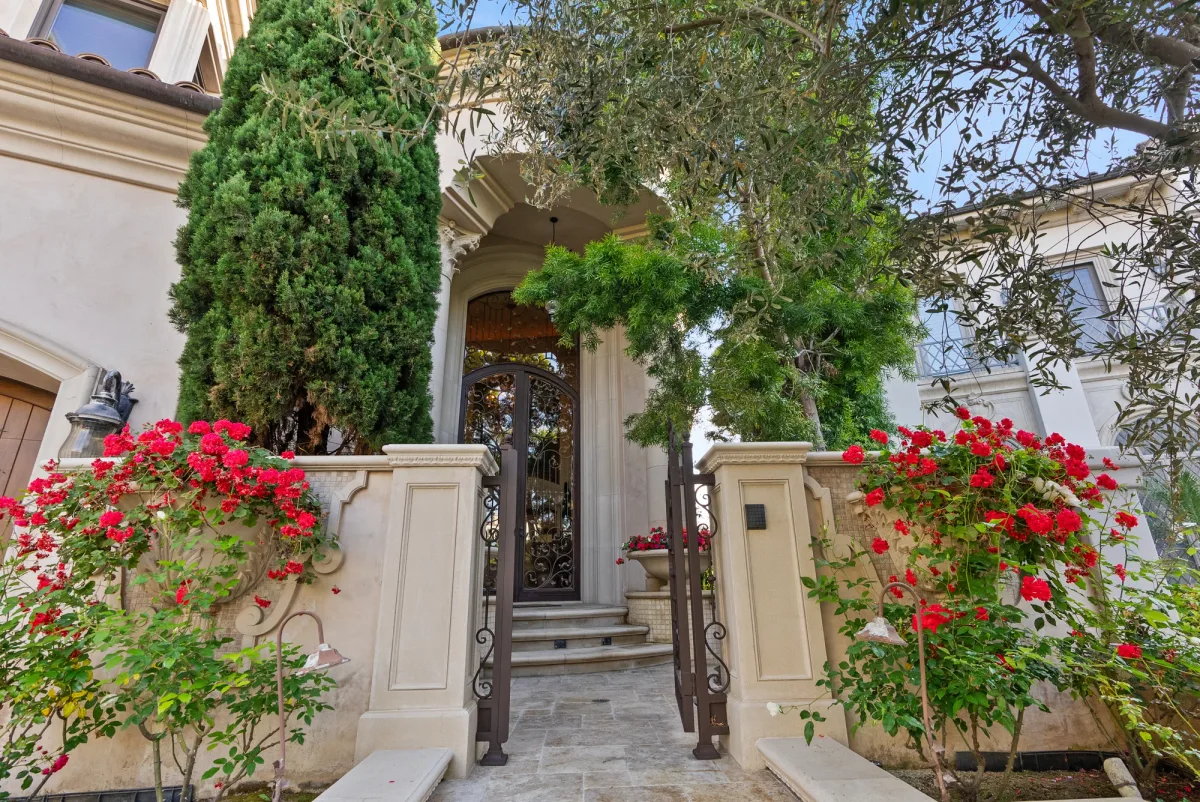 Garden entrance framed by trees and bright pink flowers